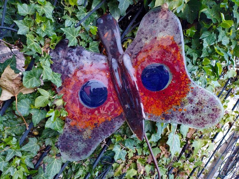 Ein farbenfroher Schmetterling aus Schmelzglas als schmuckvolle Dekoration für den Garten.